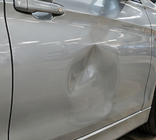 Dent in the rear door of a silver BMW 3 Series