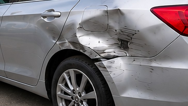 Dented and scraped rear quarter panel on a silver Honda Accord, before repair