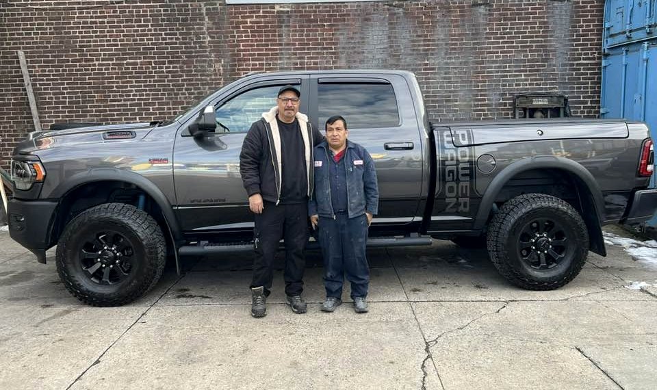 Two of the S.R. Auto team beside a pickup truck at the shop